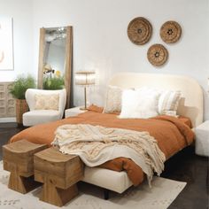 a bed sitting in a bedroom on top of a wooden floor next to two white chairs