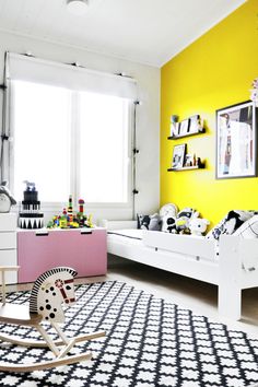 a child's bedroom with yellow walls and black and white rugs on the floor