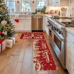 a christmas tree in a kitchen next to a stove top oven and refrigerator with santa claus doormats