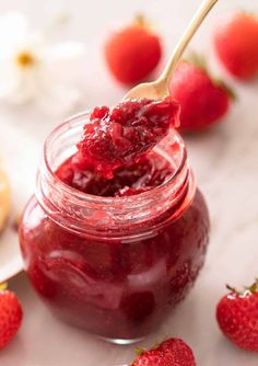 a spoon full of strawberry jam with strawberries in the background and text overlay