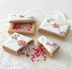 four decorated cookies sitting on top of a white doily with pink sprinkles