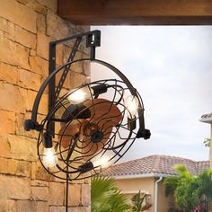 an old fashioned fan mounted to the side of a brick wall next to a palm tree