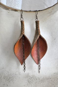 two brown leaves hanging from chains on a white wall