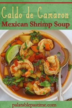 mexican shrimp soup in a white bowl with a spoon on the side and green background