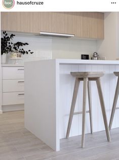 two wooden stools sitting in front of a white counter top next to a kitchen island