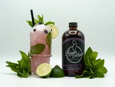 a bottle of liquor next to a glass filled with ice and limes on a white background