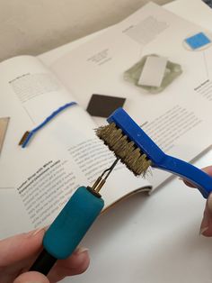 a person is holding a brush over an open book