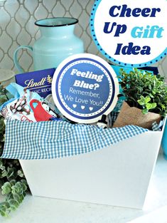 a gift box filled with blue and white items on top of a counter next to a vase