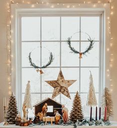 a mantel with christmas decorations and lights on it in front of a large window