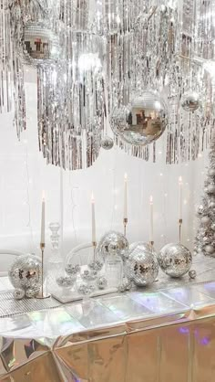 a table topped with lots of silver ornaments and christmas trees in front of a mirror wall