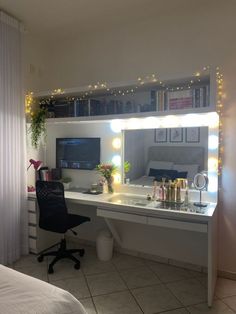 a bedroom with a desk, mirror and lights on the wall above it's headboard