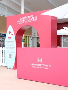 a pink booth with a surfboard on it's display wall in a shopping mall