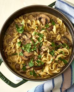 a pan filled with pasta and mushrooms on top of a table