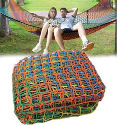 a man and woman sitting in a hammock with colorful ropes on the ground