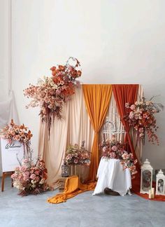 an arrangement of flowers on display in front of a curtained area with white table cloths