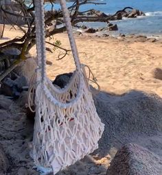 a white bag hanging from a tree on the beach