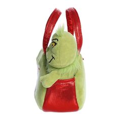 a green stuffed animal in a red handbag on a white background with clippings