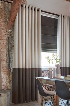 a dining room table with four chairs in front of a brick wall and two windows