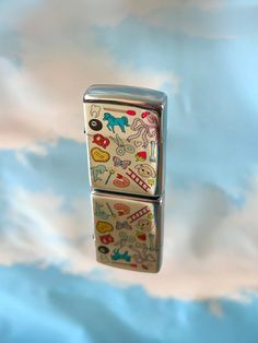 two lighters with stickers on them floating in the air above clouds and blue sky