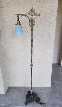 an old fashioned floor lamp with a blue shade on it's top and two keys attached to the base