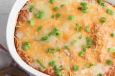 a casserole with cheese and green onions in a white dish on a table