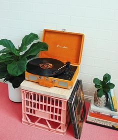 an open suitcase sitting on top of a table next to a plant and dvd's