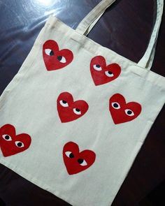 a white bag with red hearts and eyes painted on it sitting on a wooden table