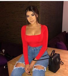 a woman sitting on top of a wooden table next to a handbag and purse