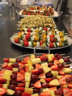 several trays of fruit and vegetable skewers on a table