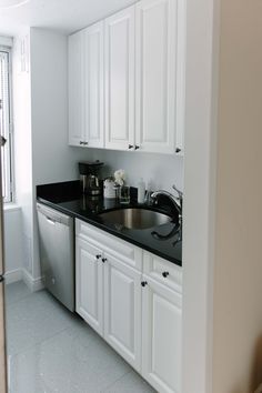 a kitchen with white cabinets and black counter tops is pictured in this image from the doorway