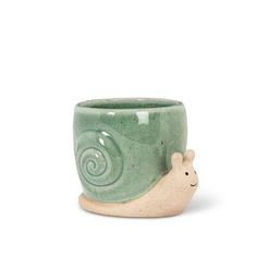 a small ceramic cup with a snail on it's side, sitting in front of a white background