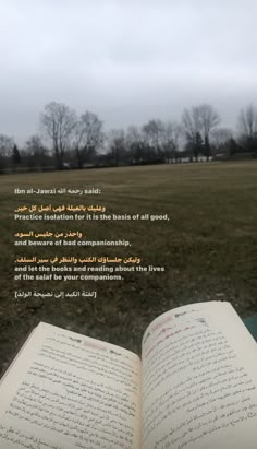 an open book sitting on top of a grass covered field