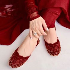 Step into elegance with our exquisite creation - the 'Pearl Ice' juttis. This gorgeous pair, adorned with captivating red embellishments, promises to mesmerize you with its beauty and provide an unparalleled level of comfort. Prepare to be star-struck as you indulge in the sheer luxury of these juttis. The upper, a canvas of opulence, is crafted from a luxurious velvet base that not only feels sumptuous against your skin but also adds a touch of sophistication to your ensemble. The rich red embellishments intricately woven into the design are the crowning jewels of this pair, turning every step into a graceful dance. What sets the 'Pearl Ice' apart is the scalloped neckline - a design element that we hold dear. The delicate scallops add a unique charm, making this pair perfect for those wh Pakistani Khussa, Red Bridal Shoes, Bling Makeup, Desi Aesthetics, Punjabi Jutti, Star Struck, Footwear Design, Scalloped Neckline, Velvet Texture