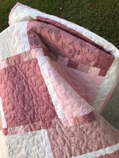 a pink and white quilt is laying on the ground