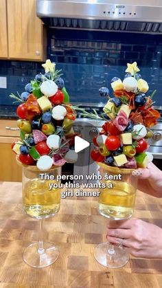 two wine glasses filled with fruit on top of a wooden table next to a stove