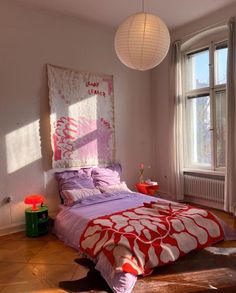 a bedroom with a large bed and two lamps hanging from the ceiling over it's headboard