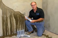 a man sitting on the ground with some paint sticks in front of him and another painting behind him