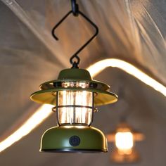 a green light hanging from the ceiling in a room with white walls and lights behind it