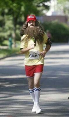 a man with long hair and beard running in a race wearing red shorts, yellow shirt and white socks