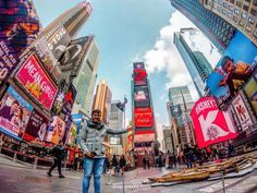 a woman standing in the middle of a busy city with lots of tall buildings and billboards