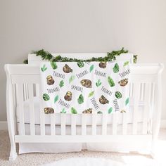 a white crib with a green and brown baby blanket hanging from it's side