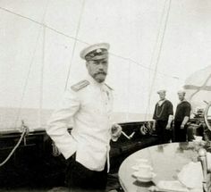 a man in uniform standing on the deck of a boat with other men around him