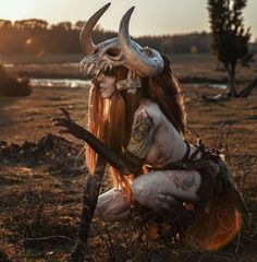 a woman with long hair and horns sitting on the ground