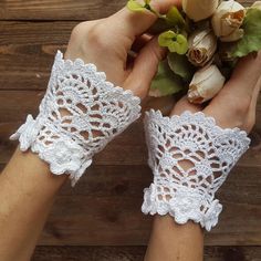 two hands are holding flowers and lace gloves