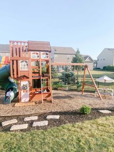 a wooden play set in the middle of a yard with a slide and climbing frame