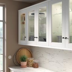 a kitchen with white cabinets and glass doors on the front, along with a potted plant