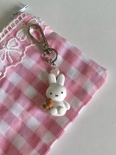 a pink and white checkered cloth with a keychain shaped like a bunny