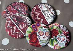 four buttons with designs on them sitting on a polka dot tablecloth, one has a skull and the other has roses