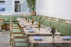 an empty restaurant with green booths and wooden tables set up for lunch or dinner,