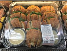 a display case filled with lots of sandwiches and dips on top of plastic trays